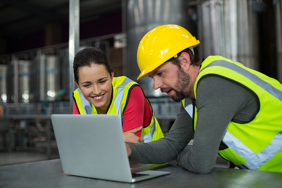 Two manufacturing workers look at a laptop for lean manufacturing principles.