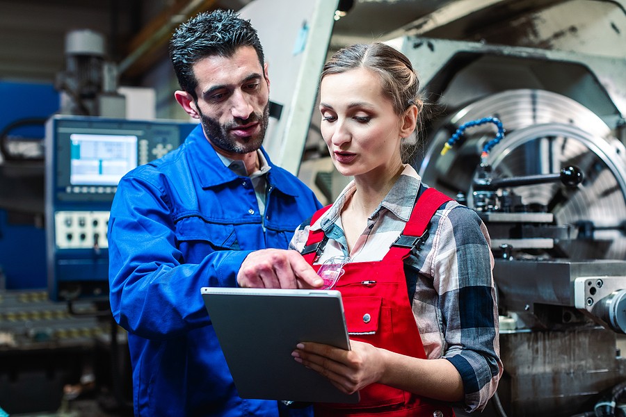 Workers talking in a manufacturing plant choose CNC machining.