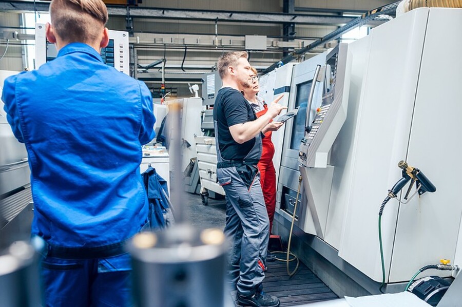 Technicians operating CNC lathe machines in an industrial manufacturing facility