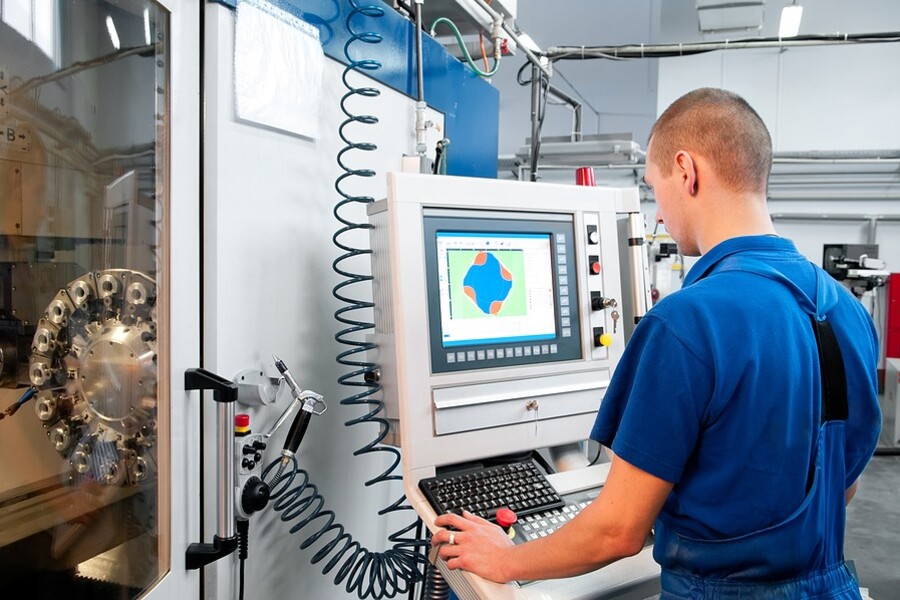 CNC machine operator programming a CNC milling machine in a manufacturing facility