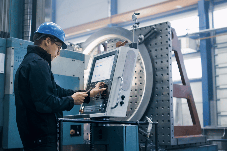 Machinist operating CNC equipment in precision manufacturing facility